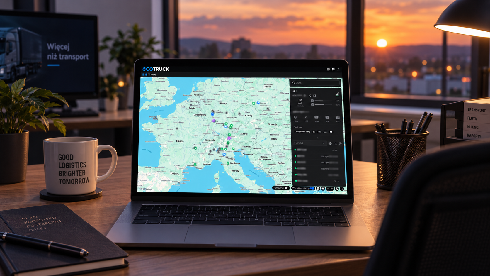 Laptop na biurku w nowoczesnym biurze z otwartym panelem ecoTRUCK i mapą Europy pokazującą lokalizacje pojazdów floty. W tle widoczny jest monitor, rośliny oraz zachód słońca za oknem.