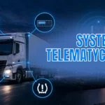 Laptop na biurku w nowoczesnym biurze z otwartym panelem ecoTRUCK i mapą Europy pokazującą lokalizacje pojazdów floty. W tle widoczny jest monitor, rośliny oraz zachód słońca za oknem.